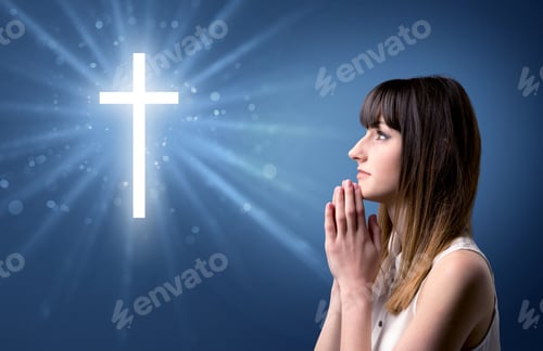 Preview: Young Woman Praying On A Blue Background With A Sparkling Cross Above Her