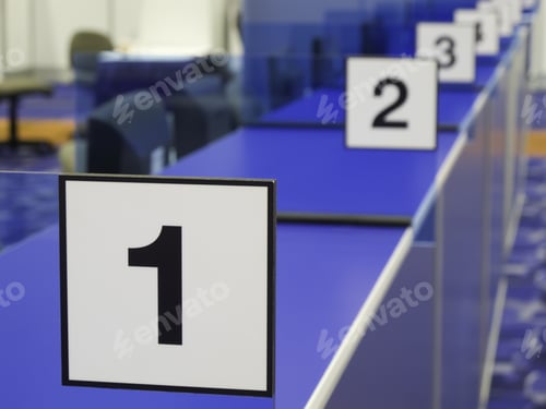 Preview: Black And White Number Signs Along Blue Registration Counter In Convention Hall (Focus On 1)