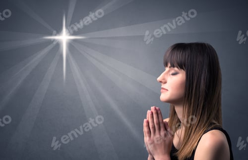 Preview: Young Woman Praying On A Grey Background With A Shiny Cross Silhouette Above Her