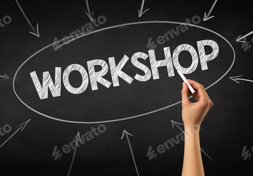 Preview: Female Hand Holding White Chalk In Front Of A Blackboard With Workshop Written On It