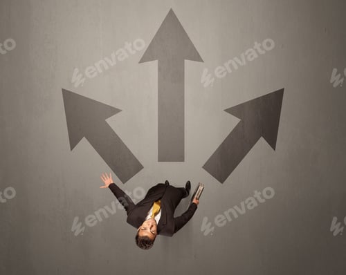 Preview: Young Contemplating Businessman Stands In Front Of Brown Arrows