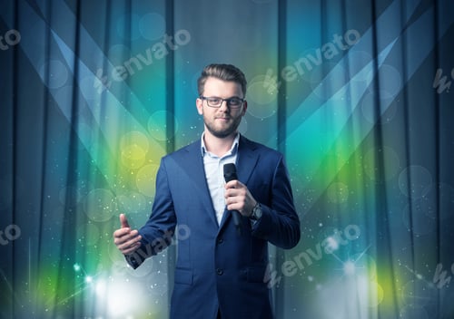 Preview: Businessman Speaking Into Microphone With Blue Curtain Behind Him