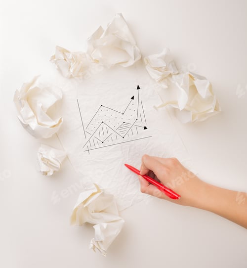 Preview: Female Hand Next To A Few Crumpled Paper Balls Drawing A Progress Chart