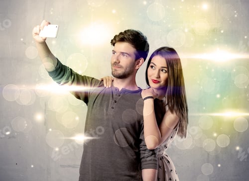 Preview: A Fresh Happy Couple Taking Selfie Photo With Mobile Phone In Front Of Colorful Lights Glitter Wall