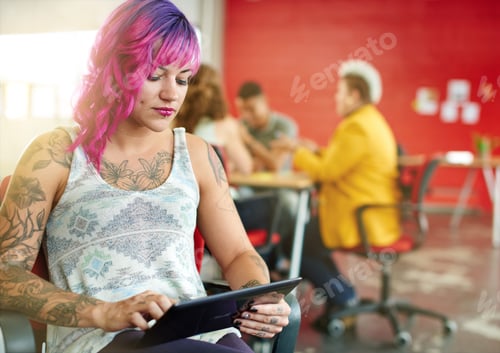 Preview: Confident And Edgy Female Designer Working On A Digital Tablet In Red Creative Office Space