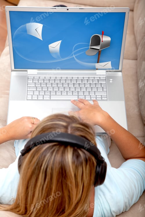 Preview: Woman Checking Her Mail On A Laptop With Headphones