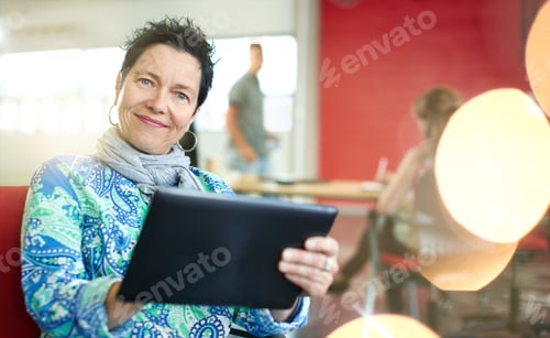 Preview: Confident Female Designer Working On A Digital Tablet In Red Creative Office Space