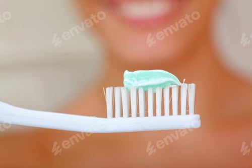 Preview: Woman Holding A Toothbrush In Front Of Her Face - Blurry Background