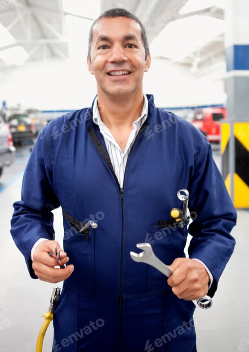 Preview: Male Mechanic Holding Tools At A Car Garage And Smiling