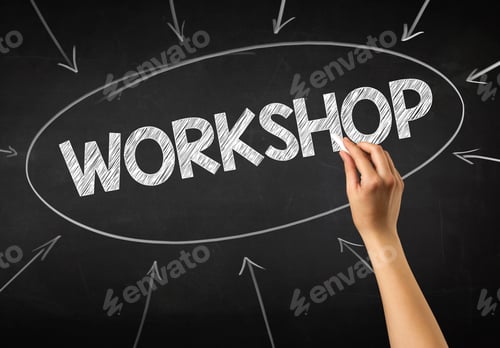 Preview: Female Hand Holding White Chalk In Front Of A Blackboard With Workshop Written On It