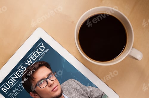 Preview: Workplace With Tablet Pc Showing Magazine Cover And A Cup Of Coffee On A Wooden Work Table Close-Up