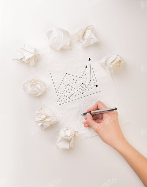 Preview: Female Hand Next To A Few Crumpled Paper Balls Drawing A Progress Chart