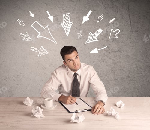 Preview: A Young Businessman Sitting At An Office Desk And Working On Paperwork With Drawn Arrows Pointing