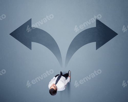 Preview: Young Smart Businessman Standing In Front Of Two Arrows Potinting To Different Ways Contemplating A