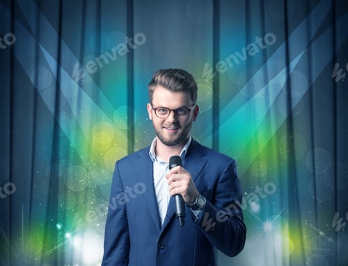 Preview: Businessman Speaking Into Microphone With Blue Curtain Behind Him