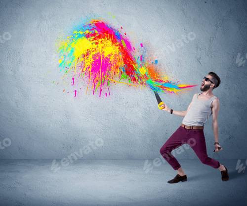 Preview: A Funny Hipster Person In Casual Urban Clothing Shouting Bright Colorful Paint On City Wall Concept