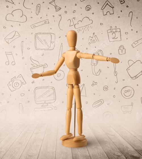 Preview: Wooden Mannequin Posed In Front Of A Greyish Background With Mixed Media Scribbles Behind It