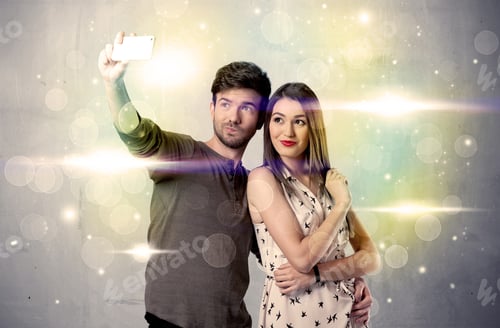 Preview: A Fresh Happy Couple Taking Selfie Photo With Mobile Phone In Front Of Colorful Lights Glitter Wall