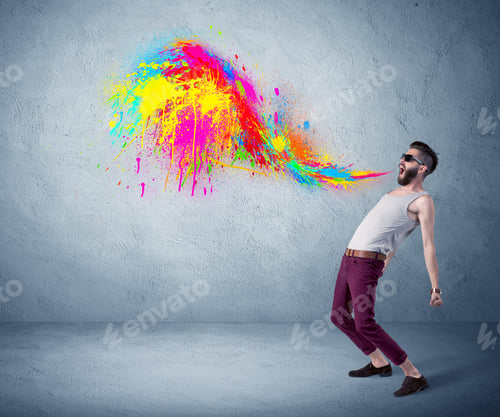 Preview: A Funny Hipster Person In Casual Urban Clothing Shouting Bright Colorful Paint On City Wall Concept