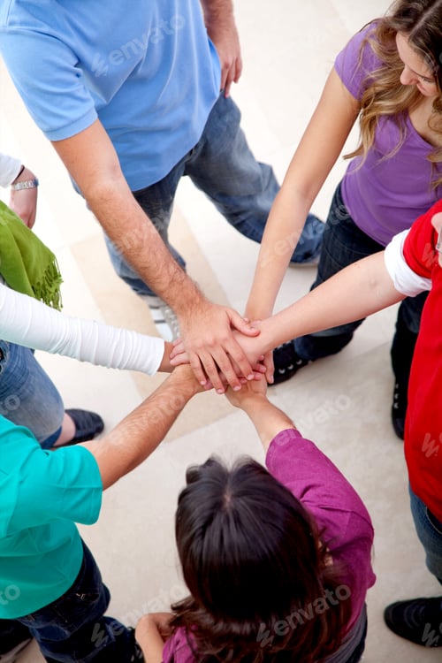 Preview: Casual Group Of Friends With Hands In The Middle Indoors