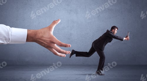 Preview: Young Miniature Businessman Running From A Big Hand With Blueish Grey Background