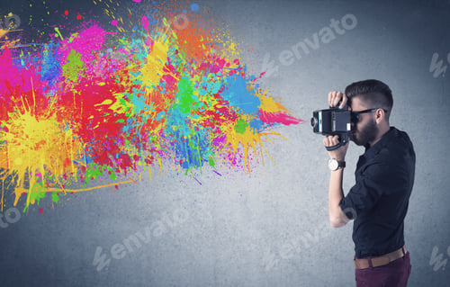 Preview: A Retro Hipster Male Taking Photograph With A Vintage Camera Of An Urban Wall With Paint Splatter