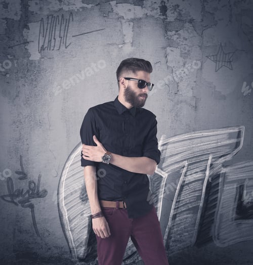 Preview: A Handsome Hipster Guy With Beard And Sunglasses Standing In Front Of An Urban Wall With Graffiti