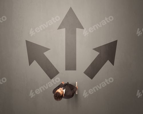 Preview: Young Contemplating Businessman Stands In Front Of Brown Arrows