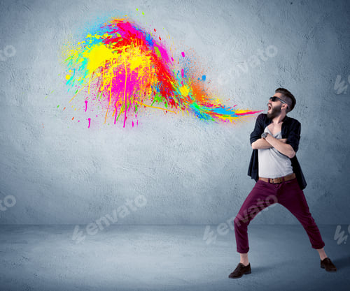 Preview: A Funny Hipster Person In Casual Urban Clothing Shouting Bright Colorful Paint On City Wall Concept