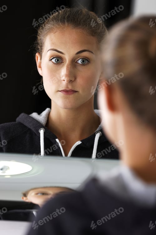 Preview: Young Woman Looking Into A Mirror In Her Bathroom