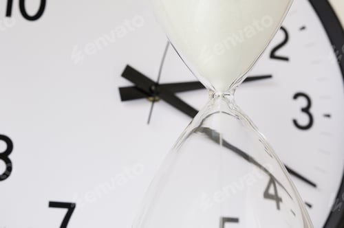 Preview: Two Measurements Of Time: White Sand Falling Inside Hourglass, With Round Analog Clock In