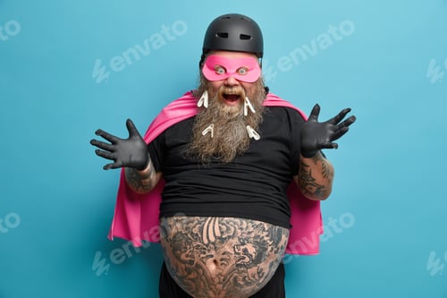 Preview: Emotional Bearded European Man Looks Excited And Cheerful Raises Hands Keeps Mouth Opened Wears
