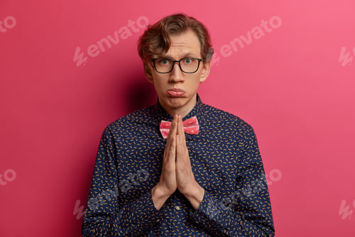 Preview: Isolated Shot Of European Man Prays For Hope, Has Faith Dreams Come True, Clasps Hands Together In