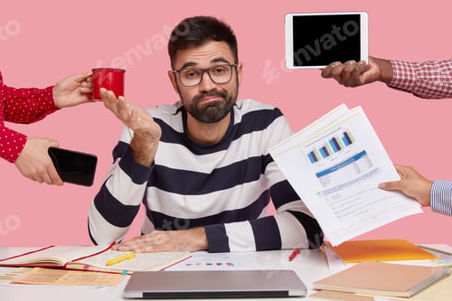 Preview: Sleepy Inexperienced Bearded Young Man With Hesitant Expression, Spreads Hand, Wears Spectacles And