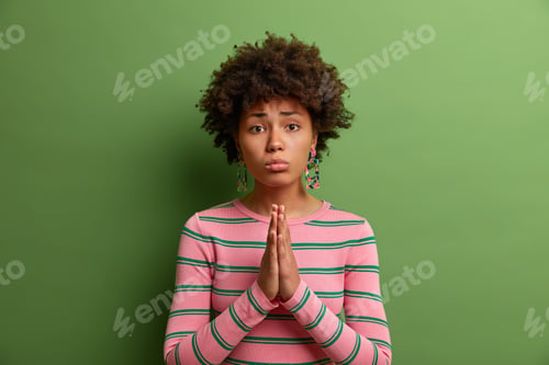 Preview: Please, I Need It Very Much. Sad Dark Skinned Female With Imploring Look, Clasps Palms Together