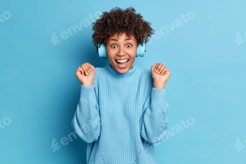 Preview: Positive Emotional Dark Skinned Woman Raises Hands Laughs Out Happily Enjoys Listening Music In