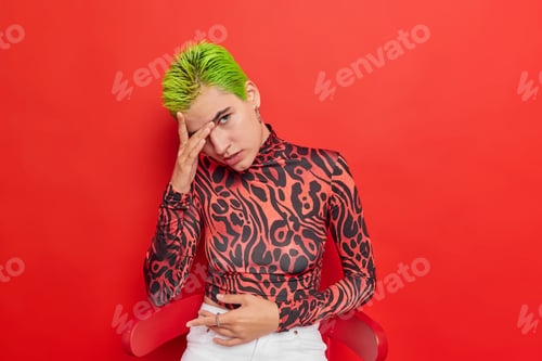 Preview: Studio Shot Of Attentive Green Haired Teenage Girl Hides Face With Hand Looks Directly At Camera