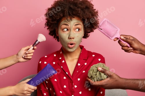 Preview: Spa, Health Care Concept. Surprised Black Young Woman With Clay Mask, Looks Aside, Dressed In