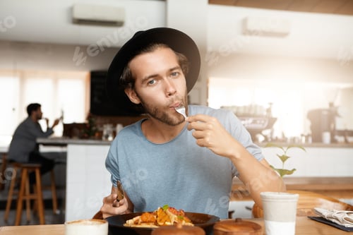Preview: Fashionable Young Man Enjoying Tasty Food For Lunch Sitting At Wooden Table Of Cozy Restaurant
