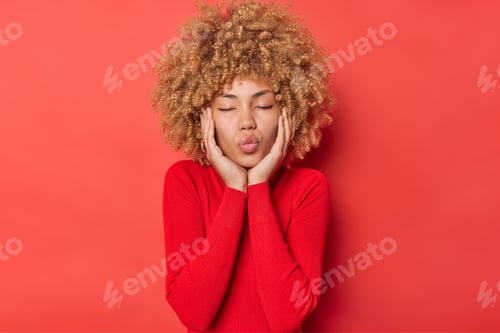 Preview: Curly Haired Young Woman Keeps Lips Rounded Awaits For Kiss Closes Eyes Has Romantic Expression