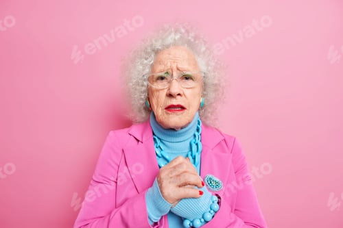 Preview: Worried Elderly Woman With Wrinkled Face Keeps Hands Together Looks Disappointed Feels Nervous