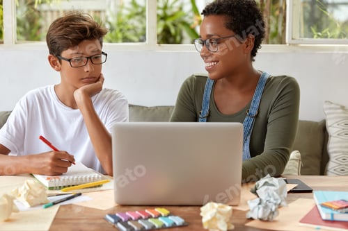 Preview: Photo Of Mixed Race Boy And Girl Classmates Watch Tutorial Video Together On Laptop Computer, Sit