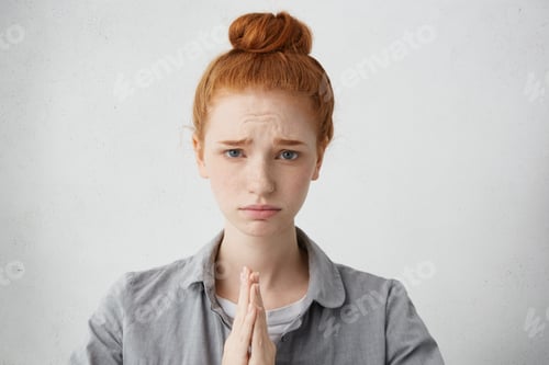 Preview: Sorrorful Religious Freckled Red-Haired Woman Holding Hands In Prayer Hoping For Fortune Frowning