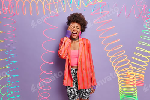 Preview: Overjoyed Dark Skinned Curly Woman Makes Face Palm, Laughs Positively, Foolishes Around, Wears