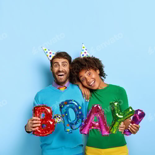 Preview: Vertical Shot Of Mirthful Lovely Diverse Woman And Man Wear Festive Paper Hats, Colorful Jumpers