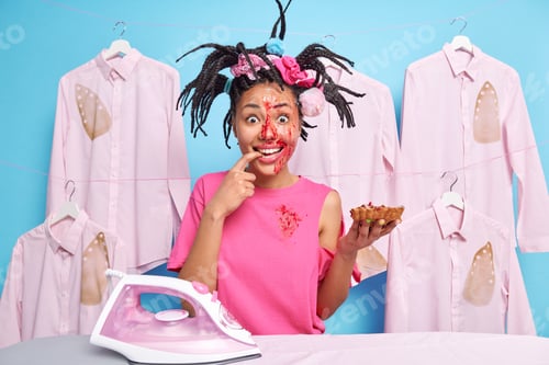 Preview: Positive Woman With Dreadlocks Enjoys Eating Tasty Pie Has Face Smeared With Sweet Jam Poses Near