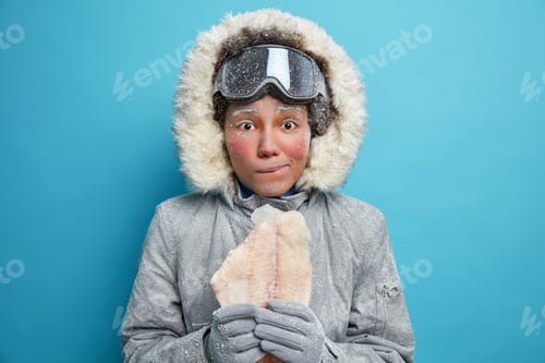 Preview: Photo Of Young Frozen Woman With Red Face Wears Warm Jacket For Cold Winter Conditions Holds Fillet