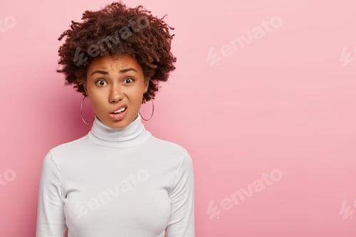 Preview: Discontent Woman With Afro Haircut, Smirks Face, Sees Something Unpleasant, Wears Hoop Earrings