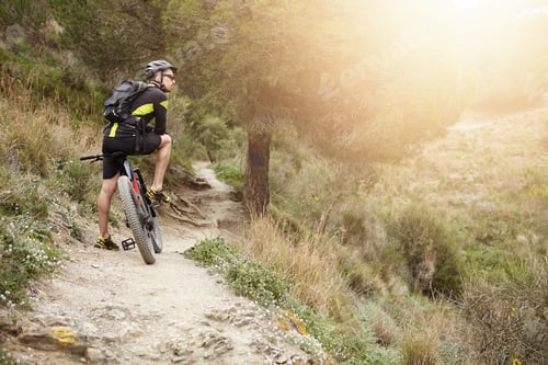 Preview: Rear View Of Cyclist Standing On Trail In Forest With His Motor-Power E-Bike Resting During Workout