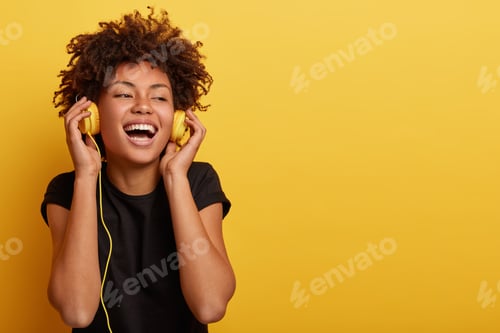 Preview: Happy Young Afro American Lady Relaxed With Great Song, Has Broad Smile, Touches Headphones